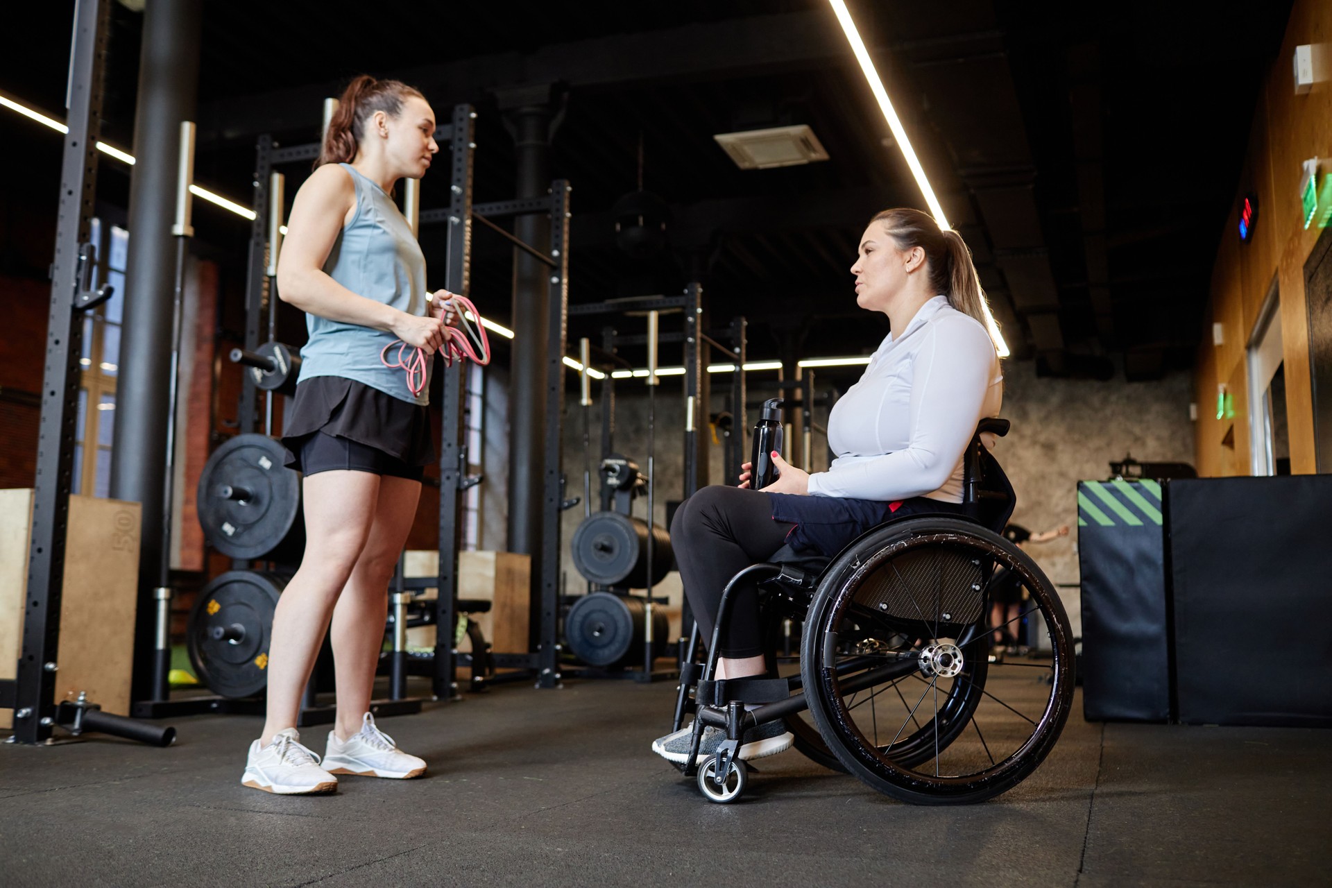 Female Fitness Trainer Assisting Woman with Disability